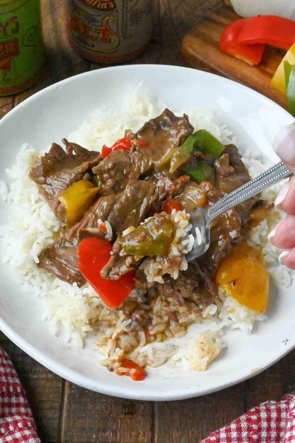 Taking a forkful of slow cooker pepper steak and white rice.