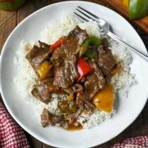 A plate of slow cooker pepper steak served over white rice.