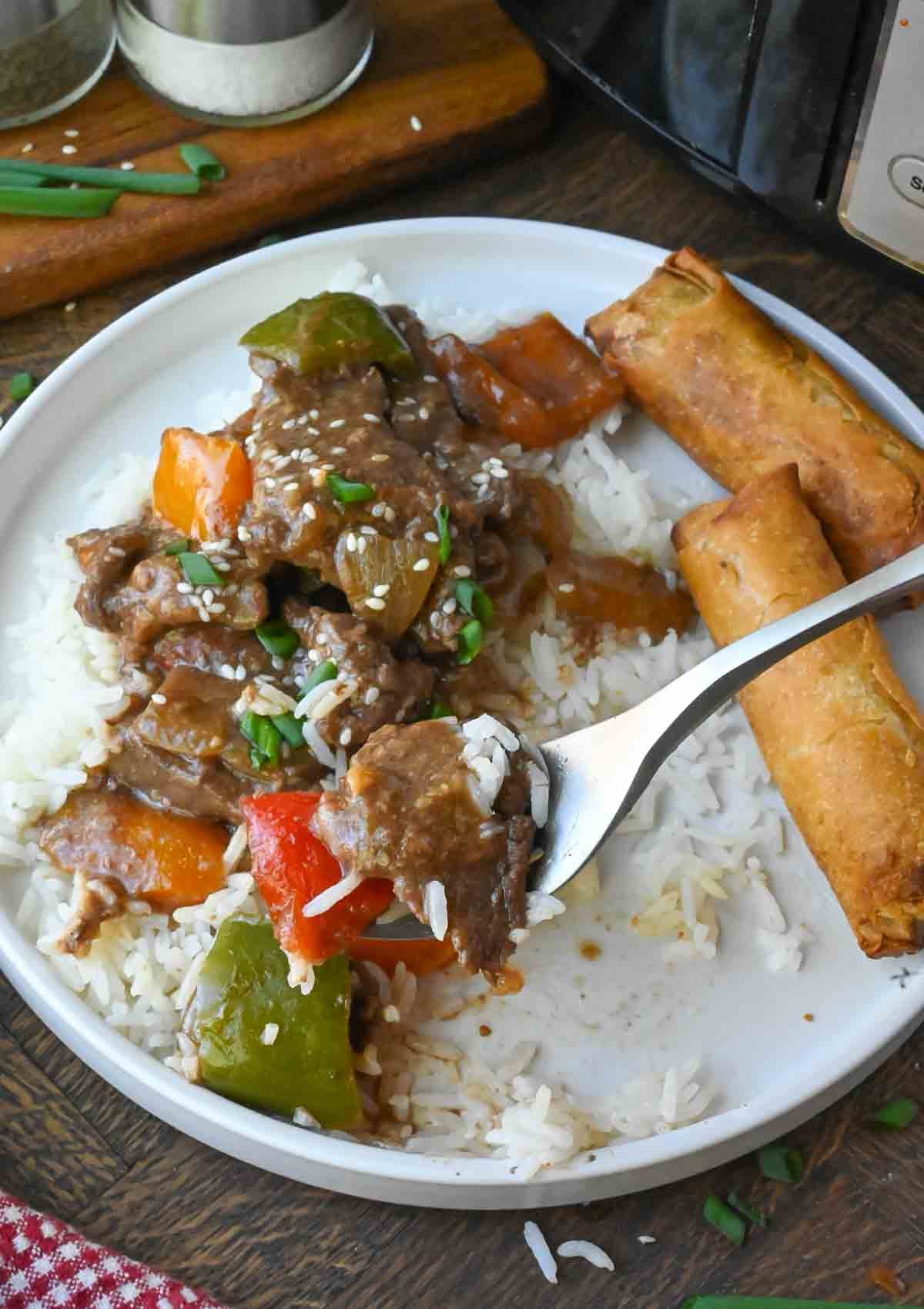 Pepper steak on a plate with white rice.