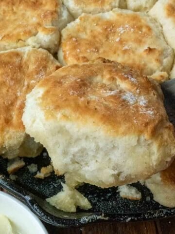 Using a spatula to lift a 7-up biscuit from a cast iron skillet.