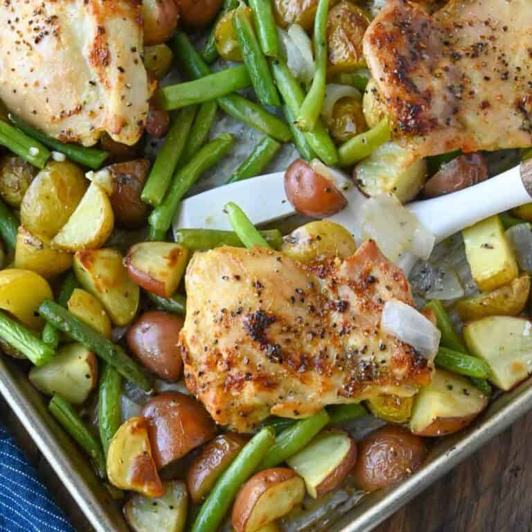 A spatula picking up a chicken thigh.
