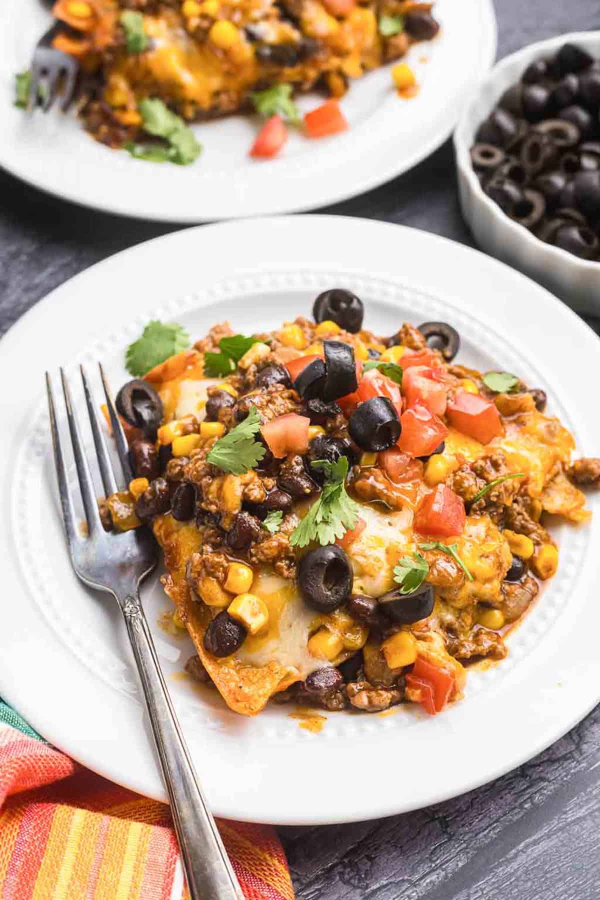 A plate with beef enchiladas and a silver fork.