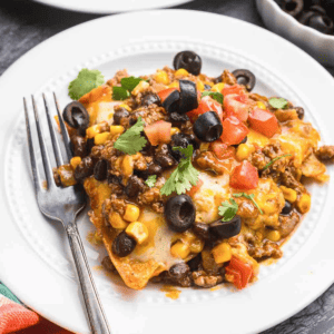 A plate of beef enchiladas with a fork.