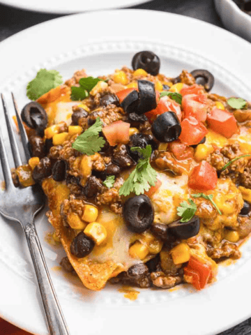 A plate of beef enchiladas with a fork.