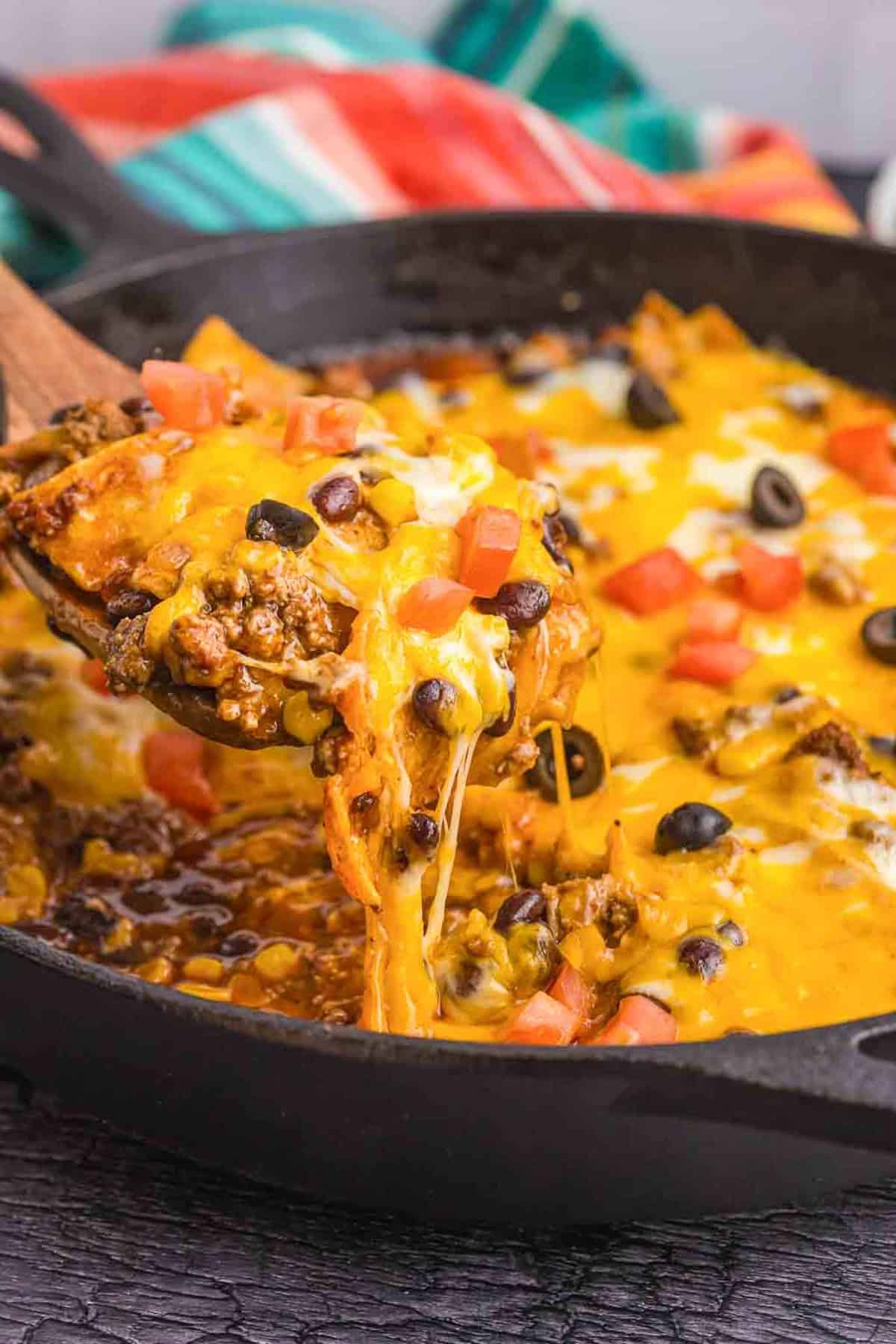 Taking a scoop of beef enchilada skillet with a wooden spoon.