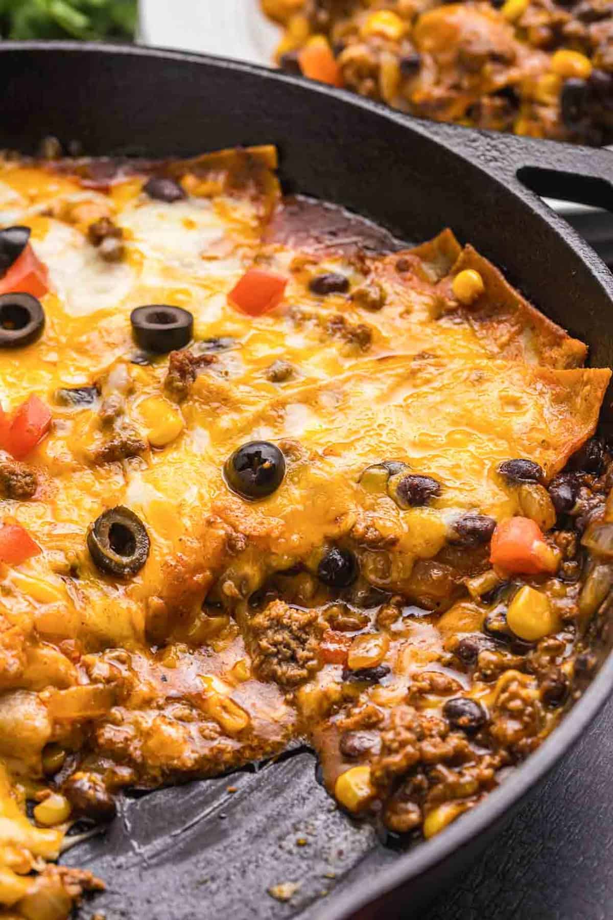 A cast iron skillet with beef enchiladas.