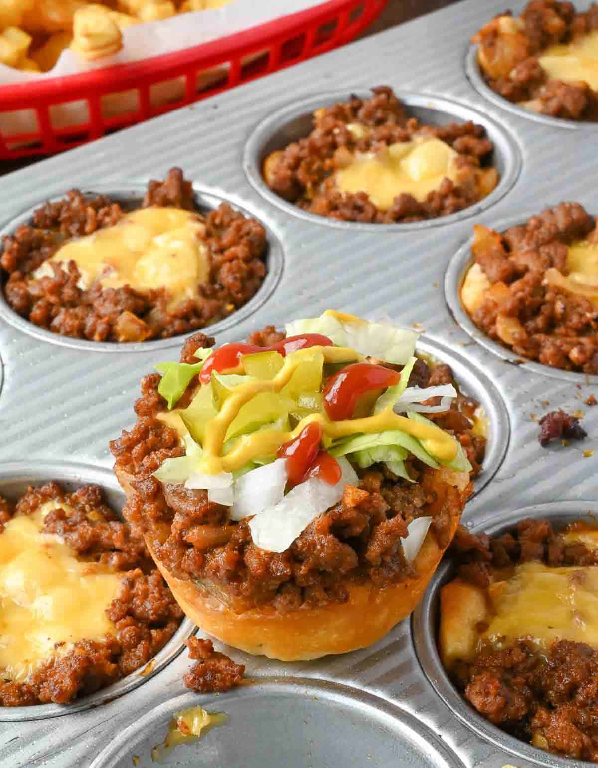 A cheeseburger cup resting on a muffin tin full of more cups.
