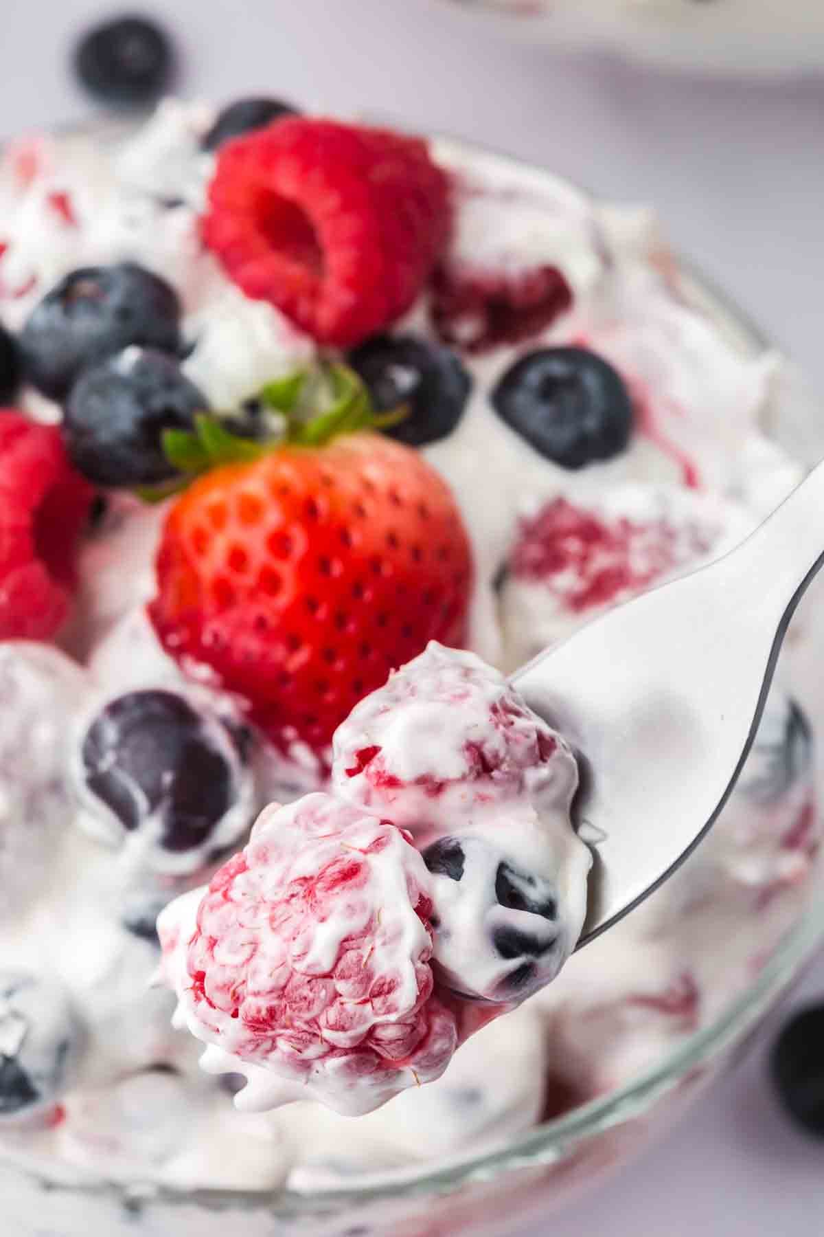 Taking a spoonful of cheesecake fruit salad.