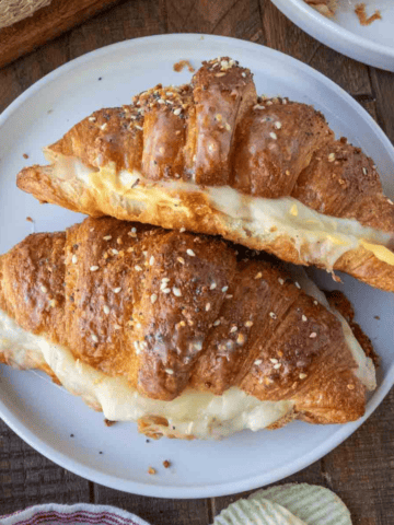 Two croissant sandwiches on a white plate.