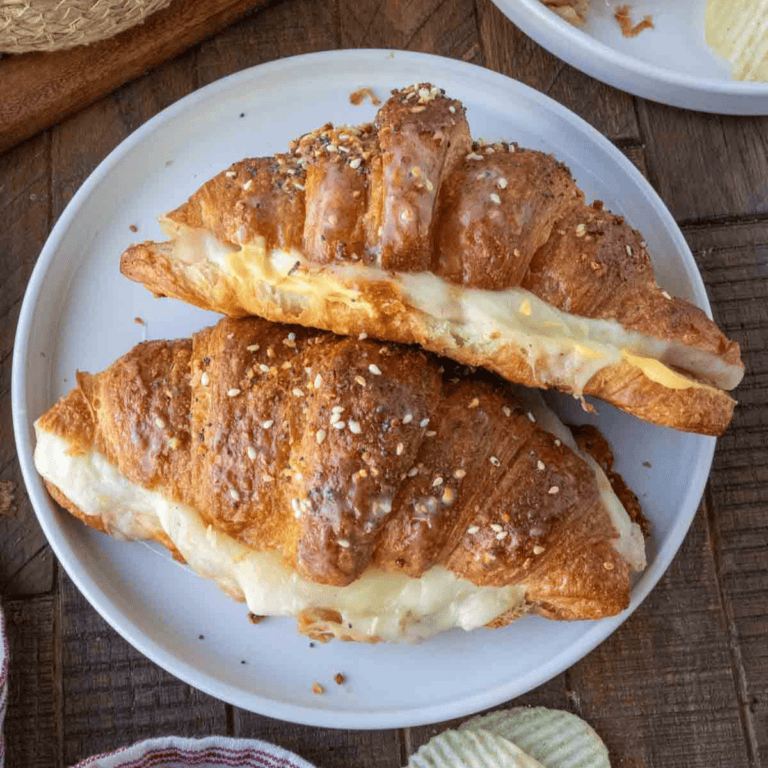 Two croissant sandwiches on a white plate.