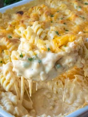 Scooping up 5 cheese mac and cheese from a baking dish.