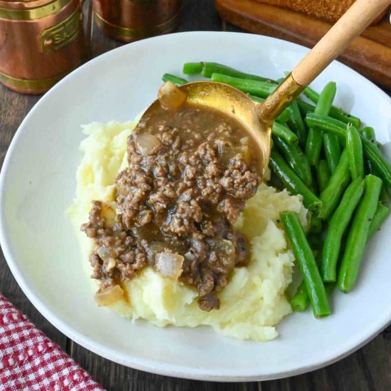 Spooning ground beef and gravy over mashed potatoes.
