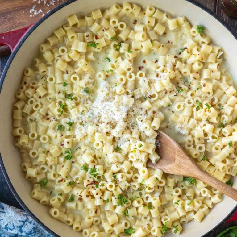 Butter noodles in a skillet with parmesan cheese on top
