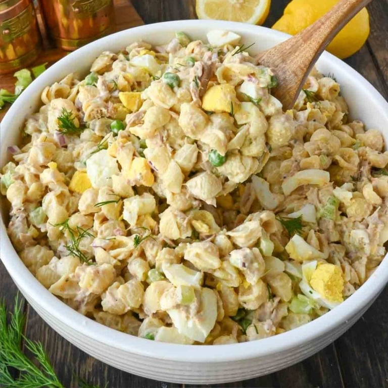 Stirring a bowl of tuna pasta salad with a wooden spoon.