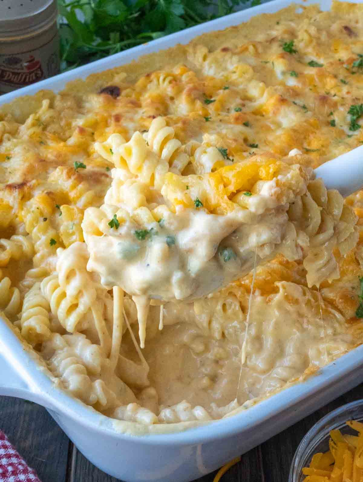 Taking a big scoop of 5 cheese mac and cheese from a baking dish.