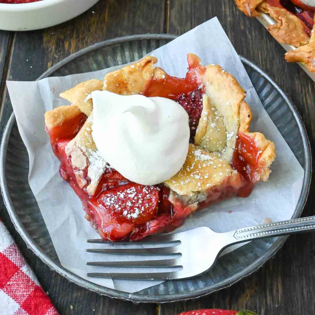 Strawberry slab pie on a plate with a dollop of whipped cream.