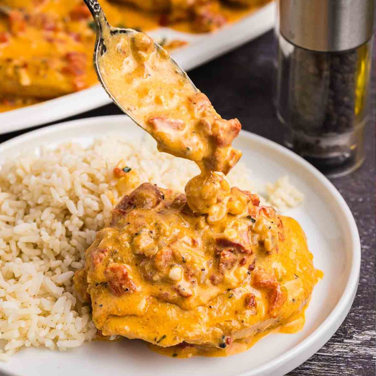 roasted red pepper chicken on a plate with white rice.
