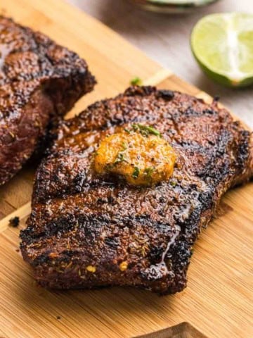 Grilled top sirloin steak on a wooden platter.