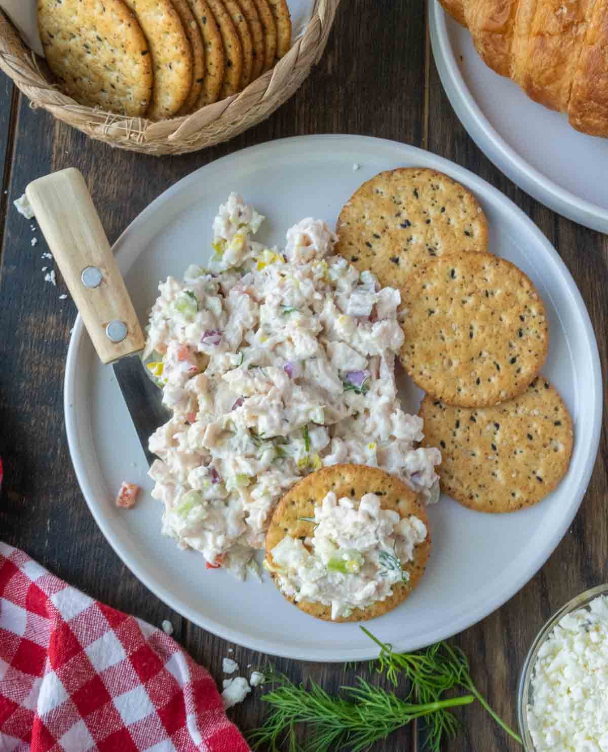 A plate with feta chicken salad and crackers.