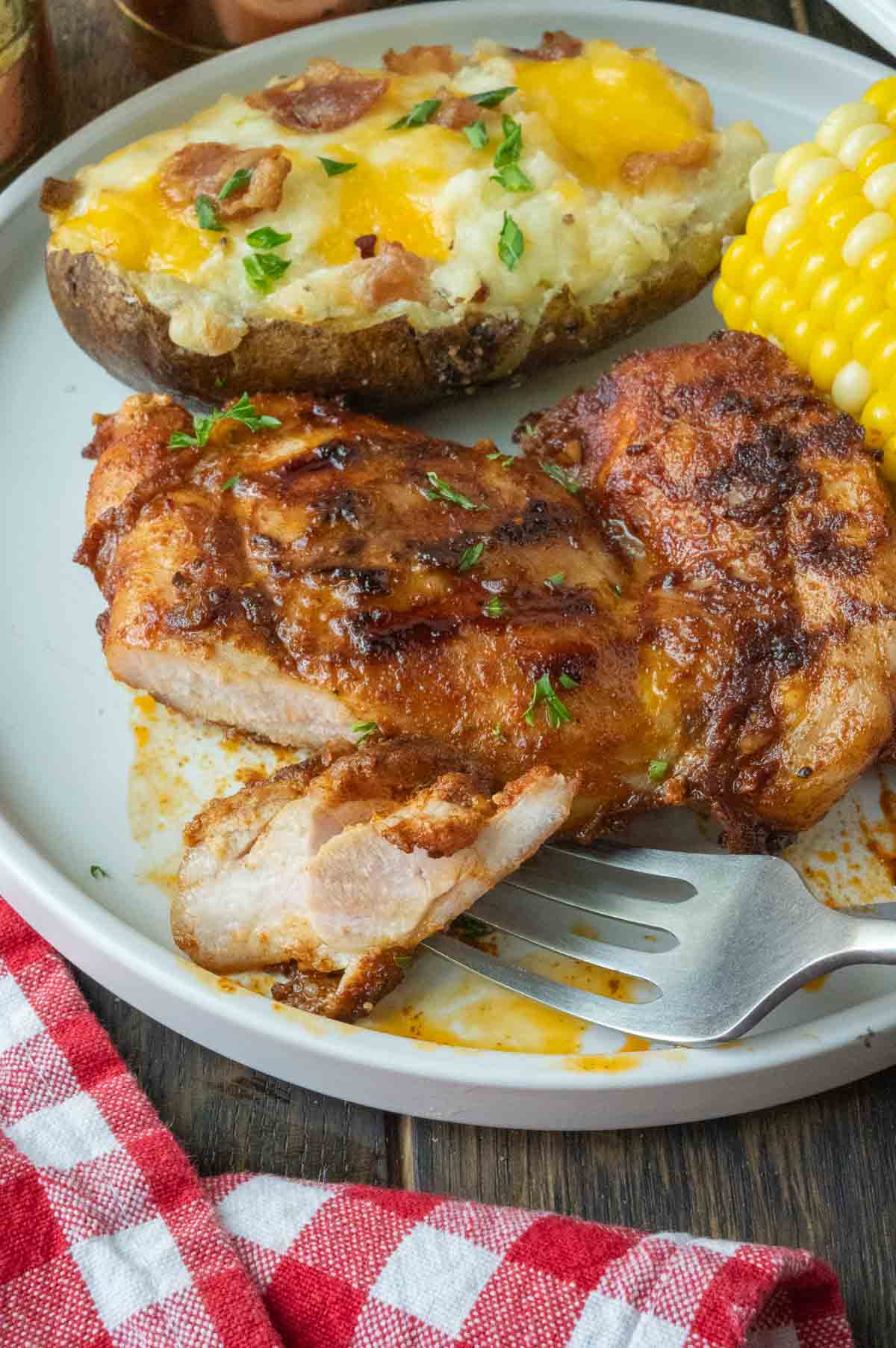 Paprika chicken thighs on a plate with a fork cutting a piece.