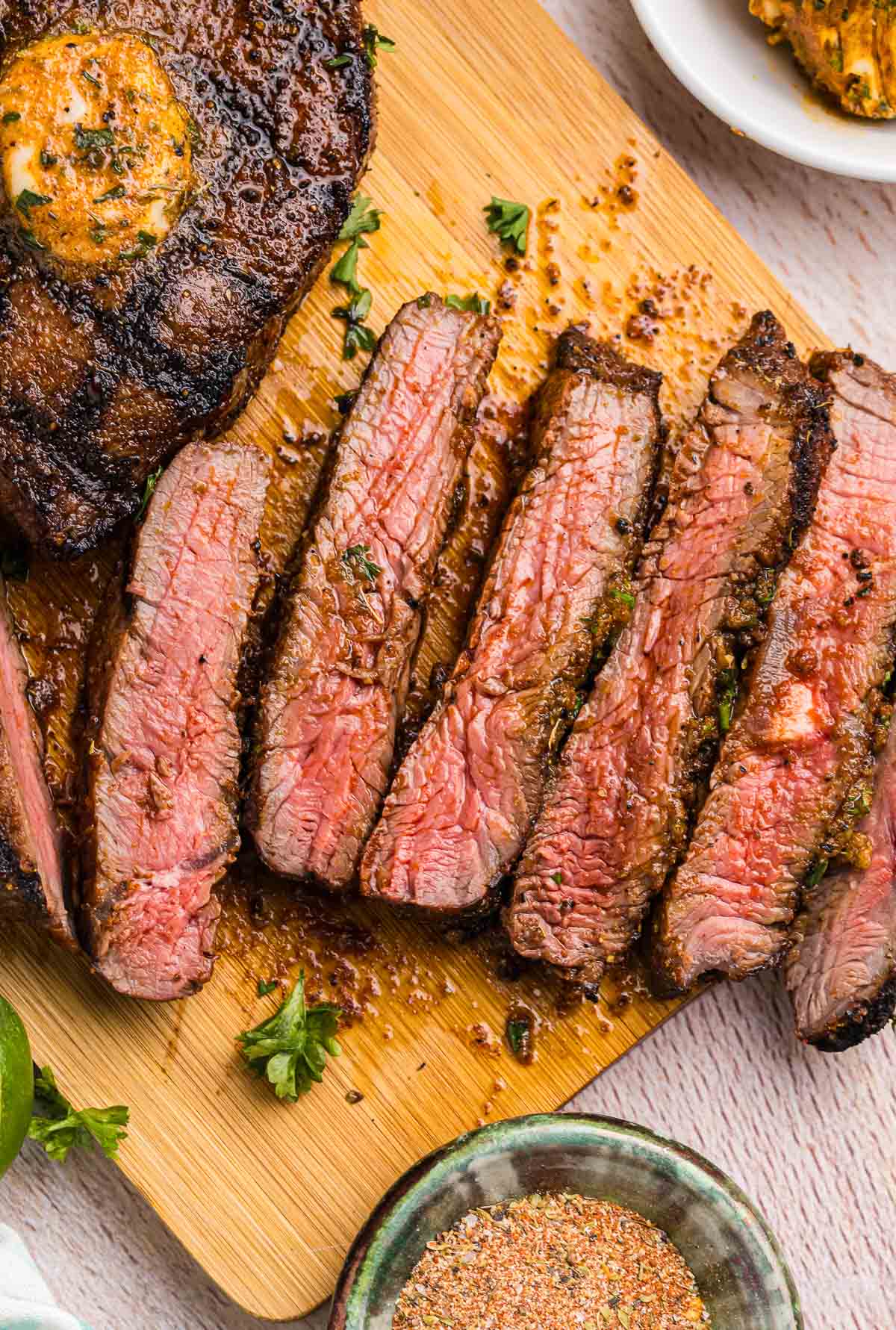 Slices of top sirloin steak on a wooden cutting board.