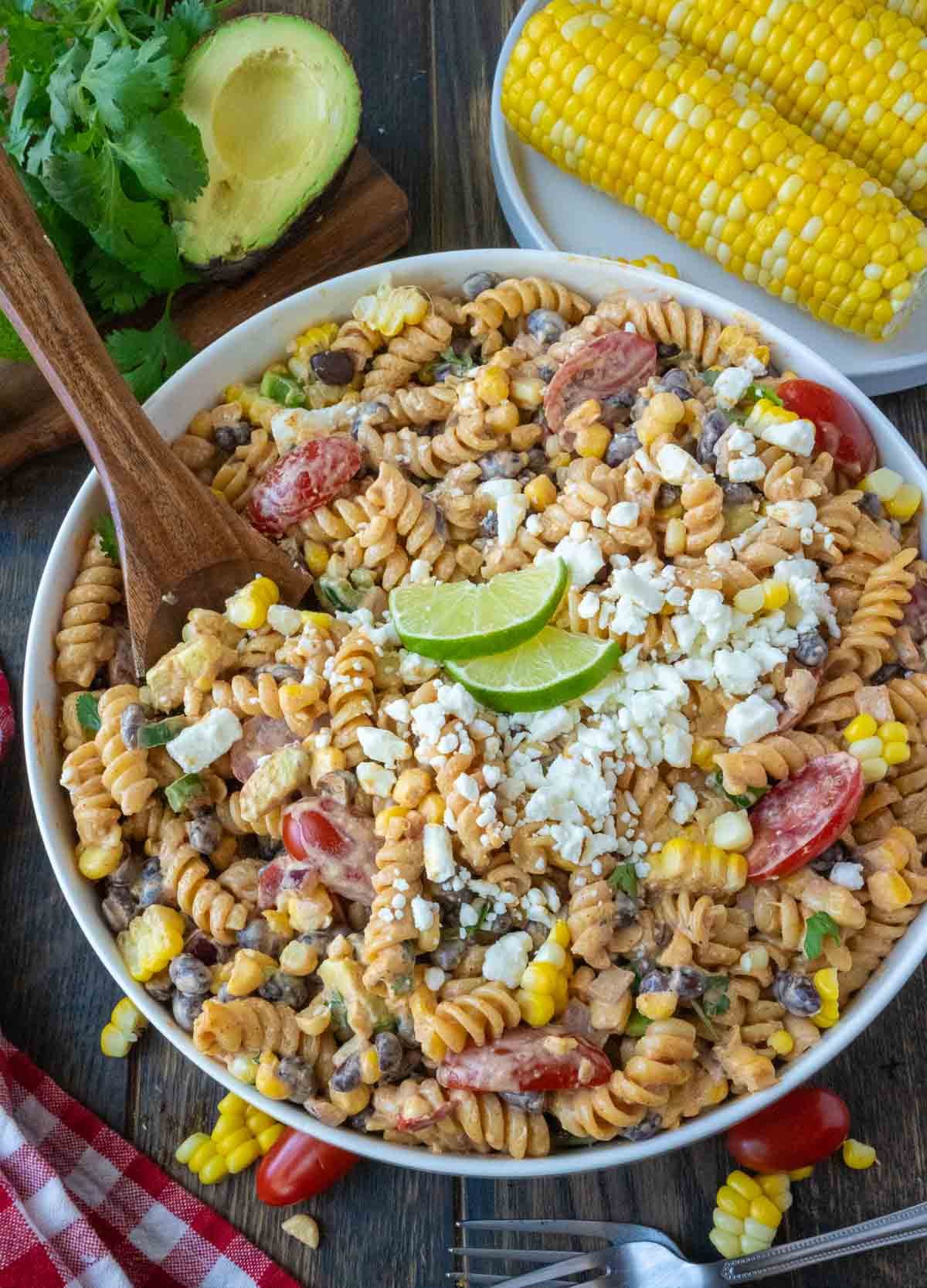 Mexican street corn salad in a bowl with a wooden spoon.