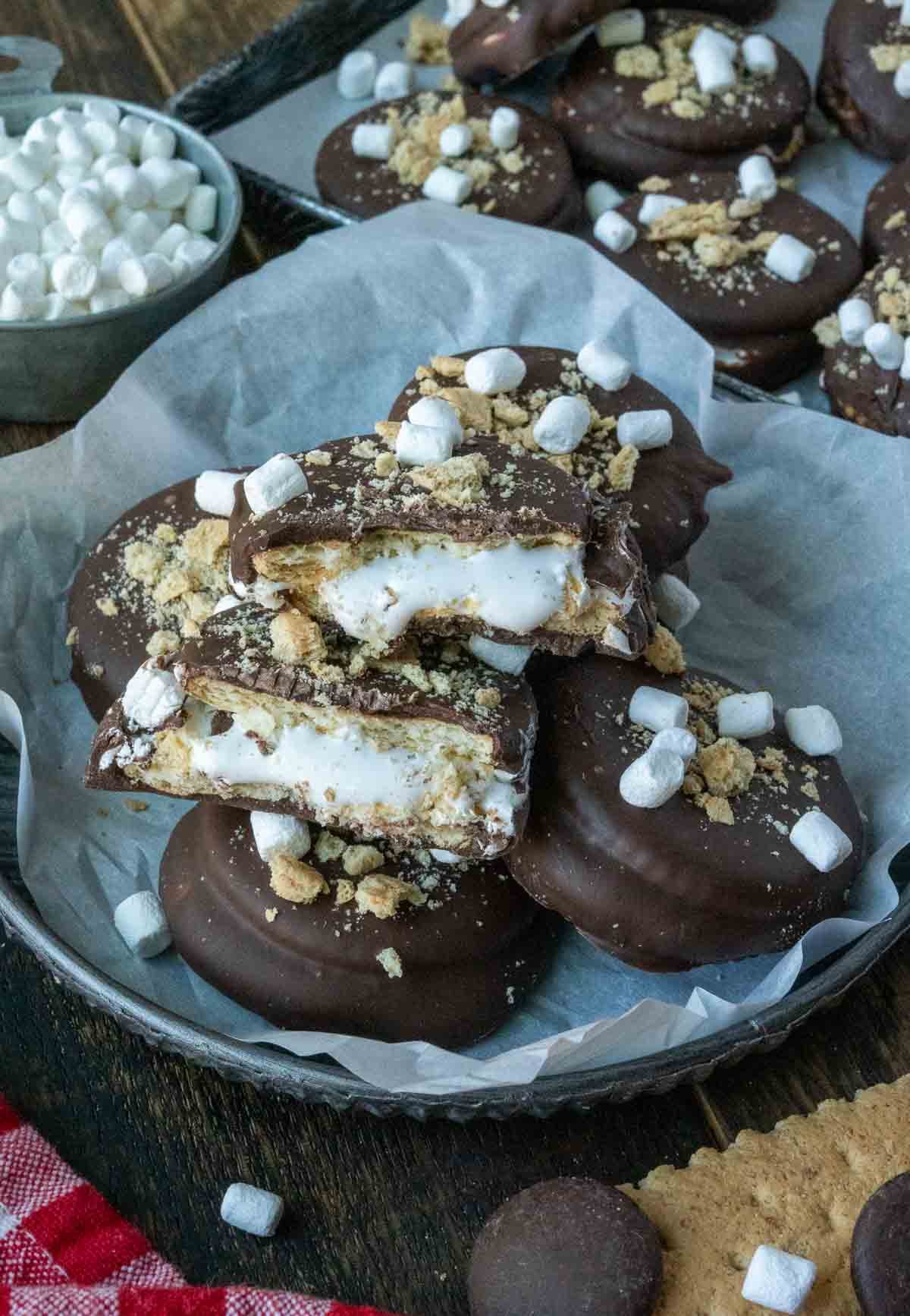A plate lined with parchment paper and stacked with ritz smores cookies.