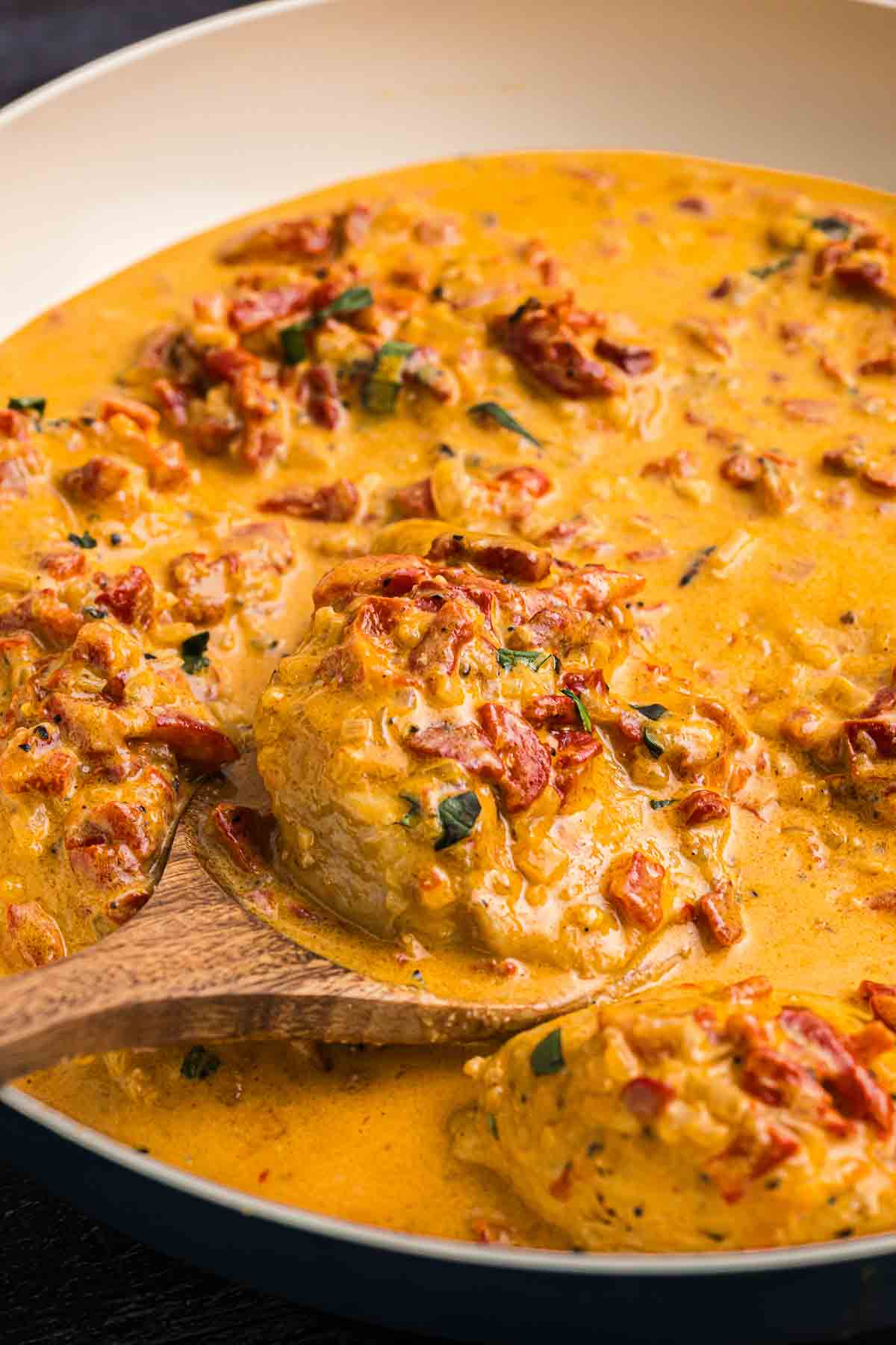Chicken in a skillet with roasted red pepper sauce.