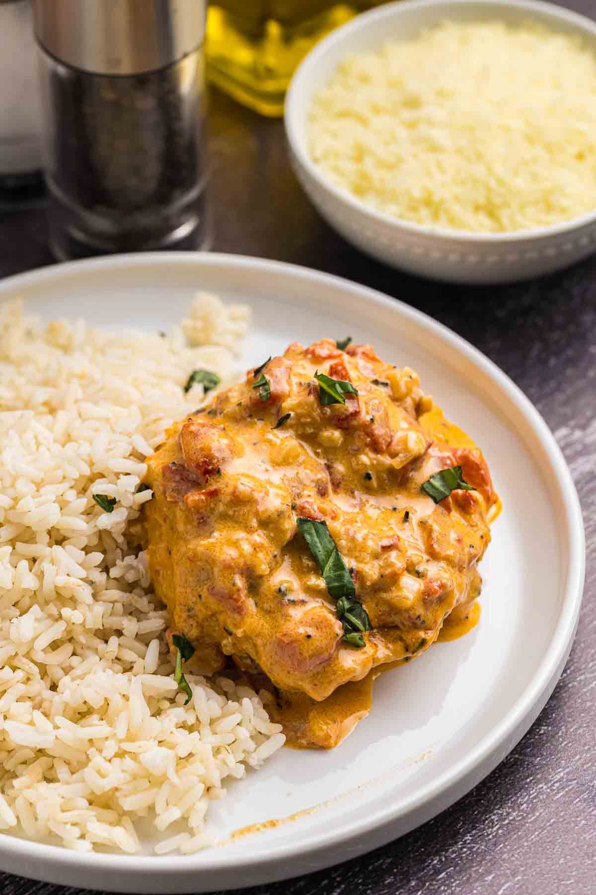 Roasted red pepper chicken on a plate with white rice.