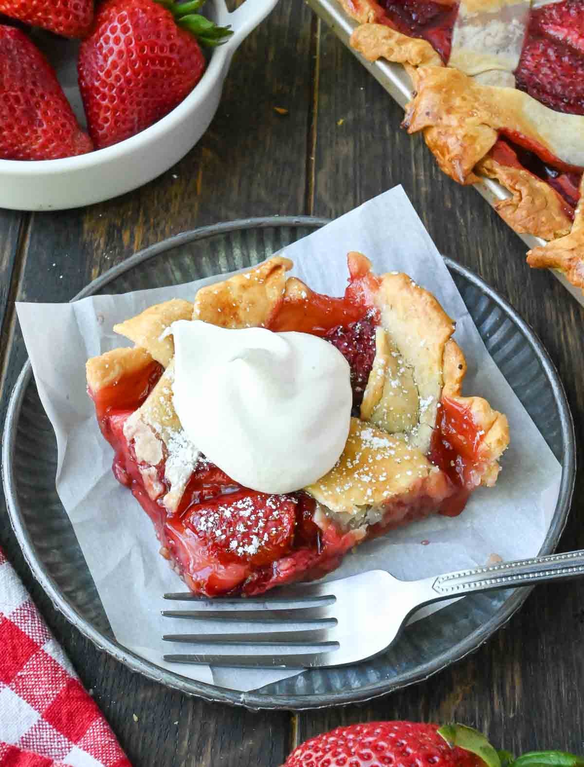 A slice of strawberry pie on a plate with a fork.