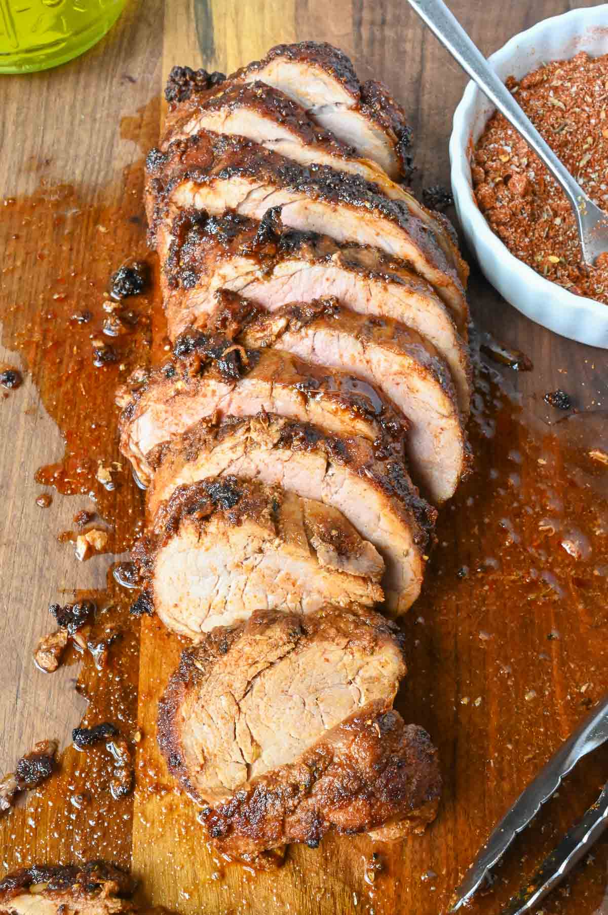 Pork tenderloin sliced on a cutting board.