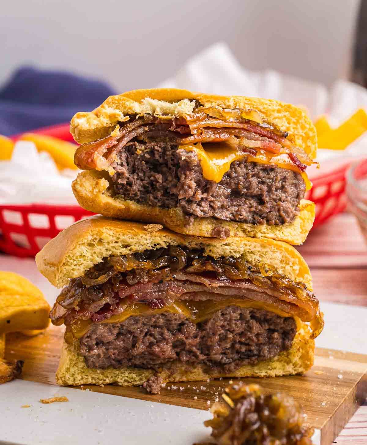 Two halves of a bourbon bacon cheeseburger on a cutting board.