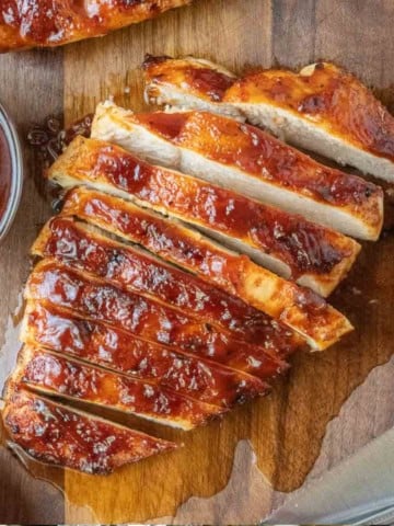Close up of sliced BBQ chicken on a cutting board.