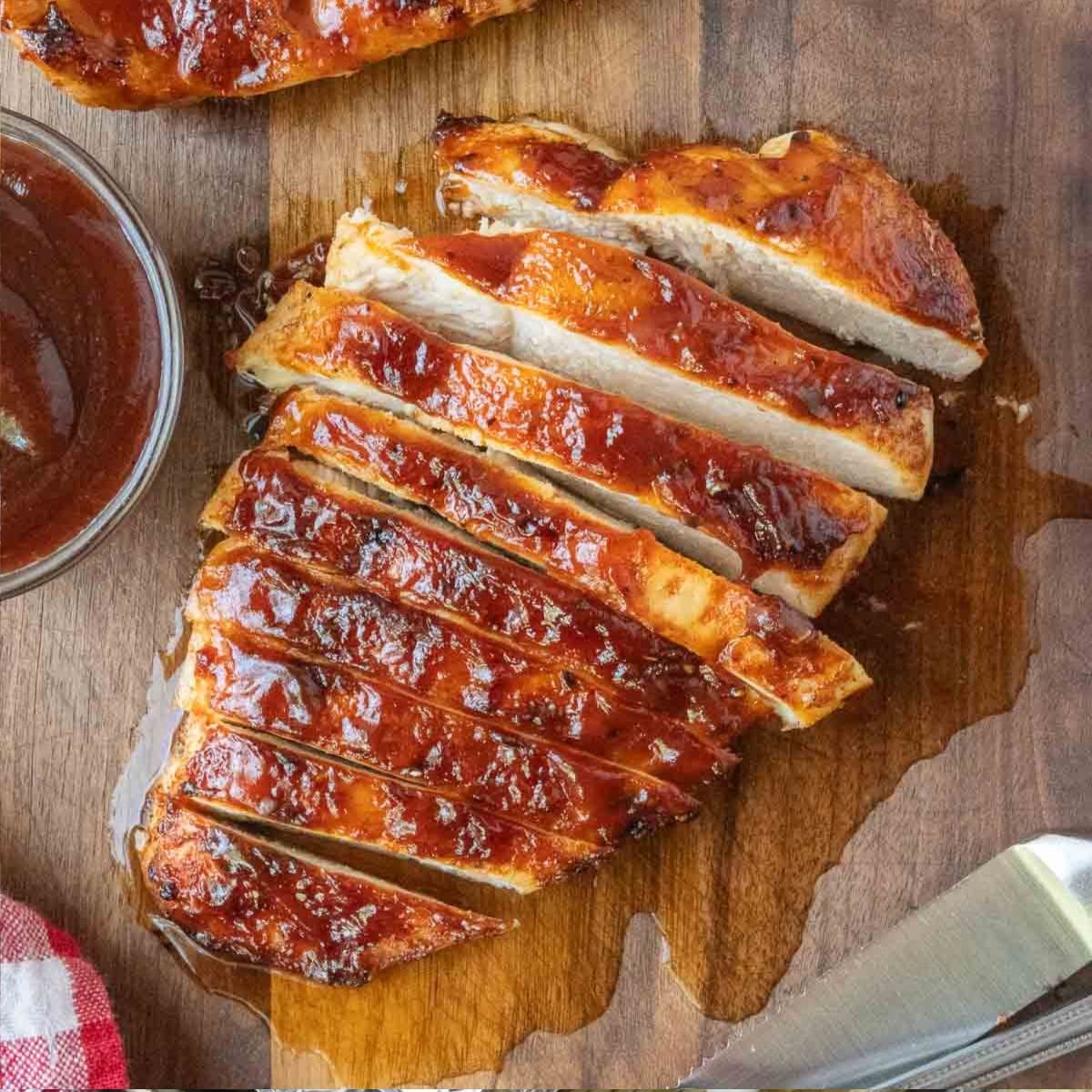 Close up of sliced BBQ chicken on a cutting board.