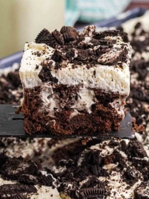 Oreo poke cake slice being picked up with a spatula.