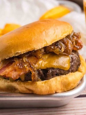 Bourbon bacon cheeseburger on a platter with french fries.