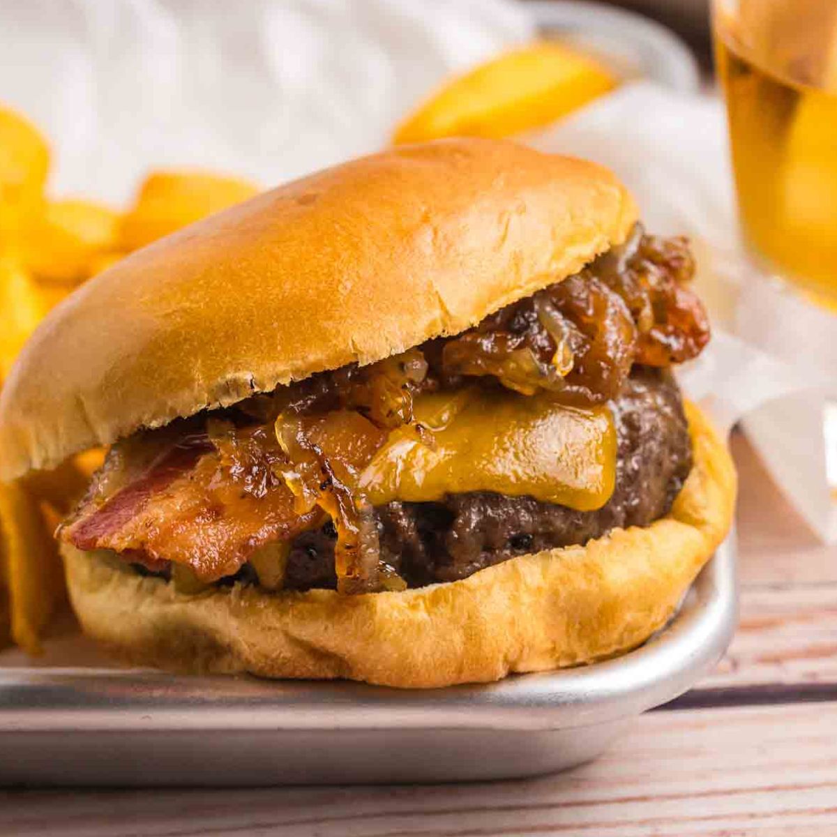 Bourbon bacon cheeseburger on a platter with french fries.