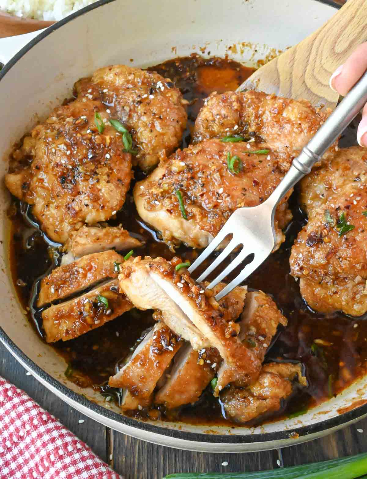 Picking up a piece of soy garlic chicken from a skillet.