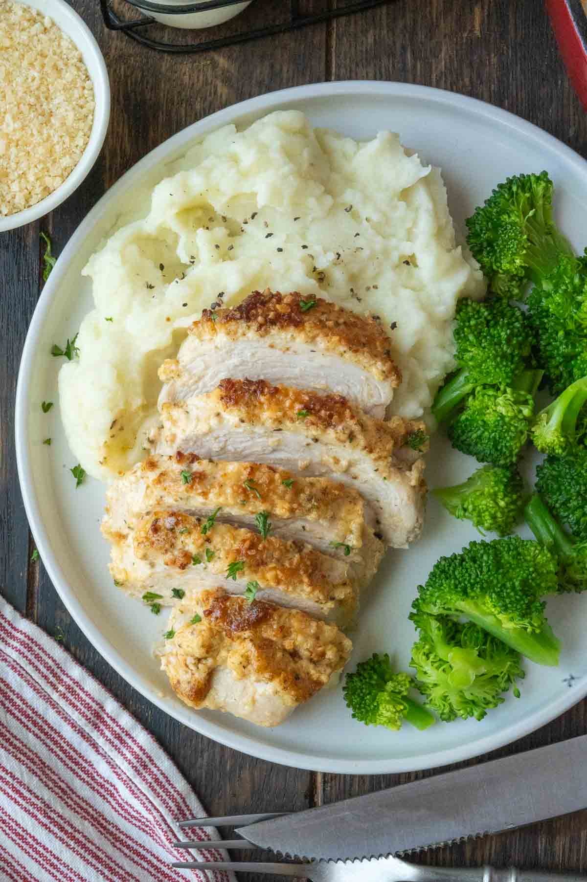 Melt in your mouth chicken on a plate with mashed potatoes and broccoli.