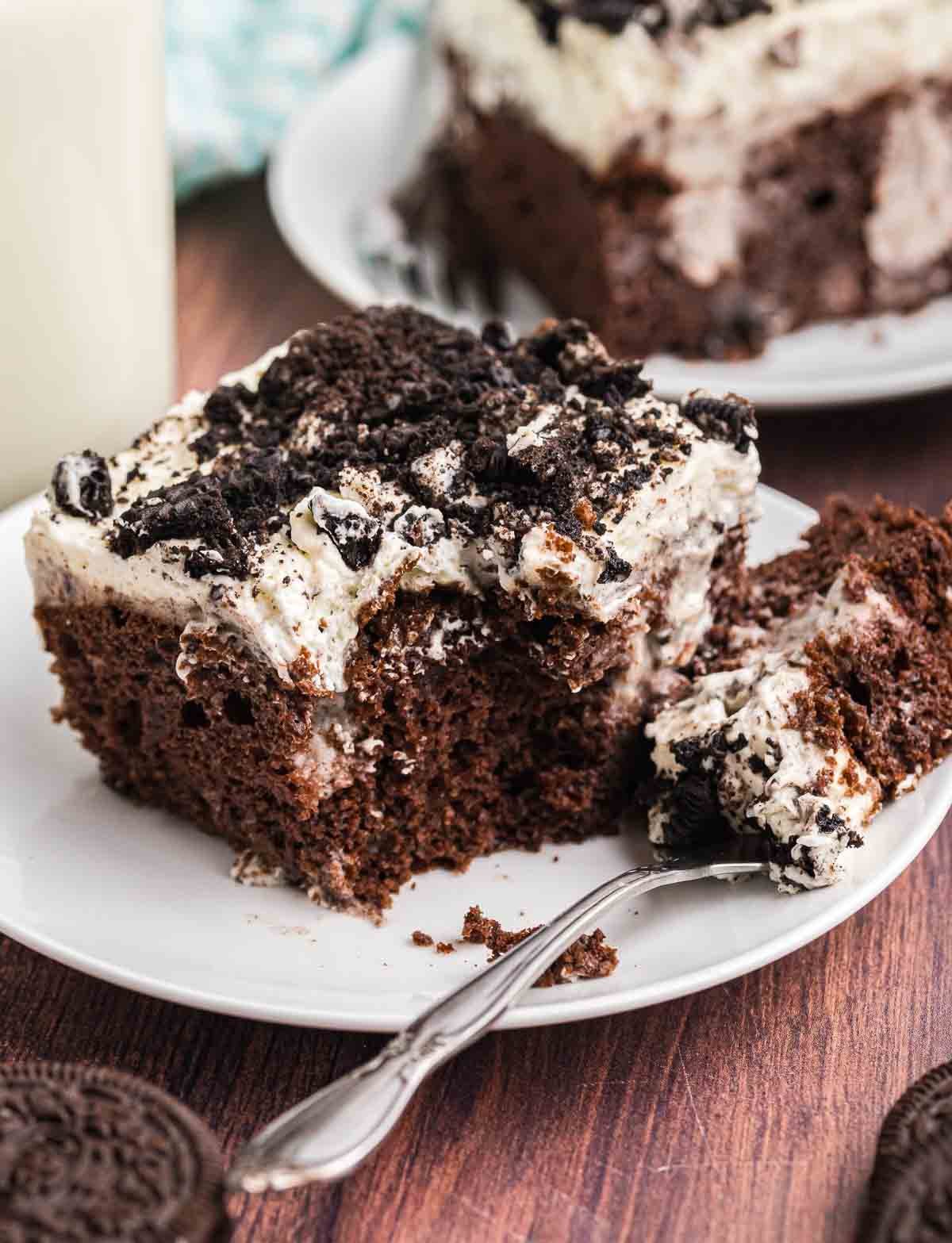 A piece of oreo cake with a fork taking a bite out of it.
