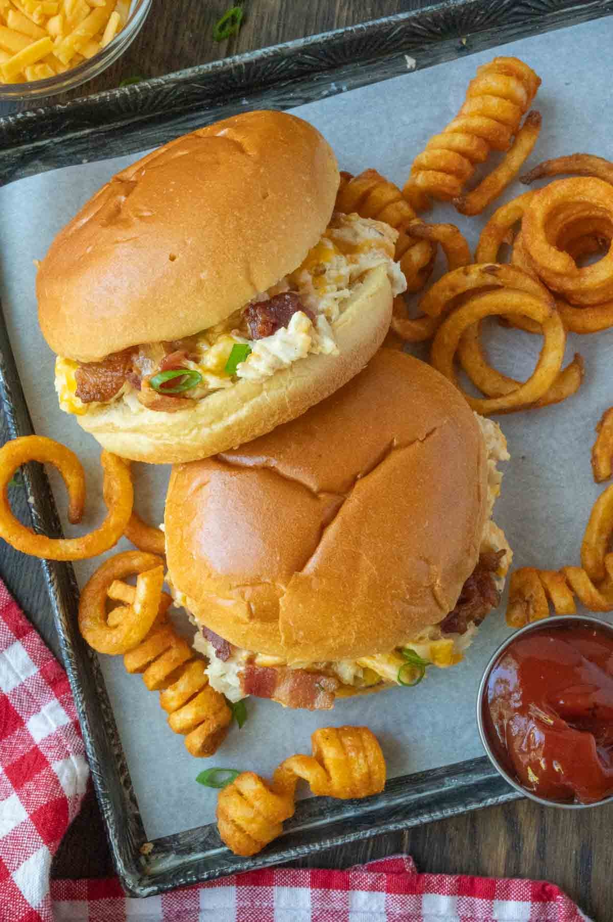 Two slow cooker chicken bacon ranch sandwiches with curly fries.