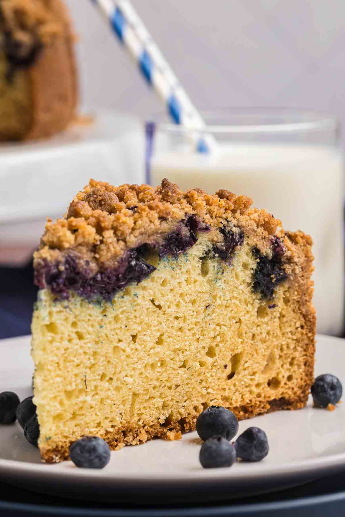 A slice of blueberry crumb cake on a plate with blueberries.