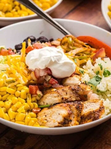 Cajun grilled chicken in a bowl with toppings and rice.