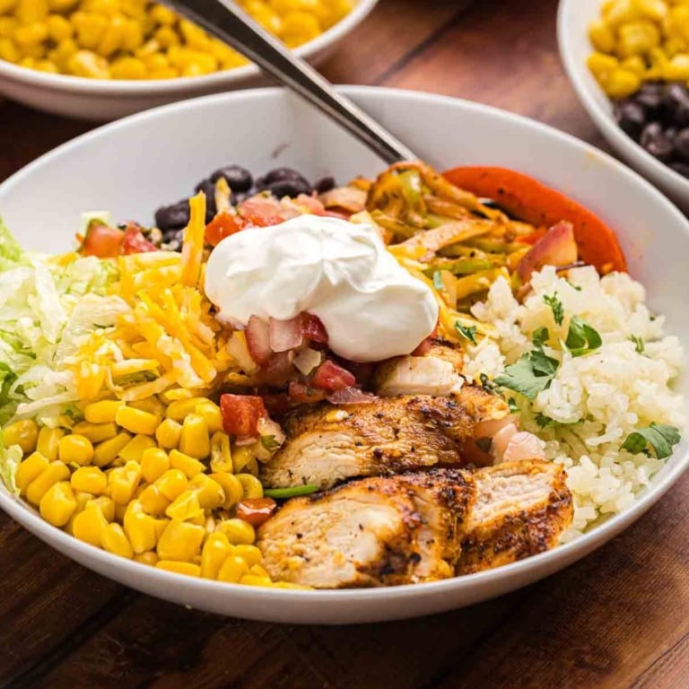 Cajun grilled chicken in a bowl with toppings and rice.