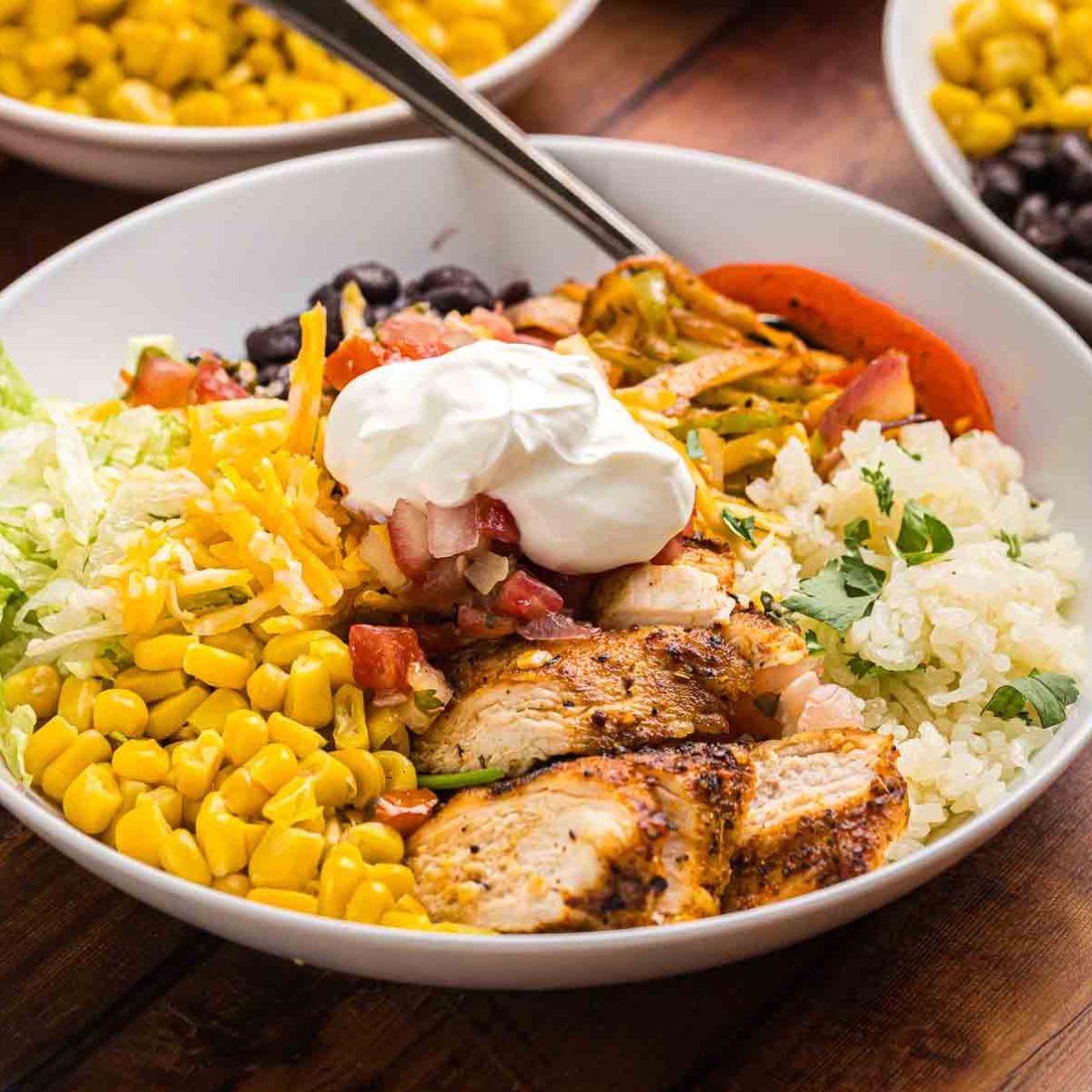 Cajun grilled chicken in a bowl with toppings and rice.