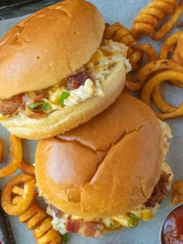 Two bacon ranch sandwiches on a pan with curly fries.