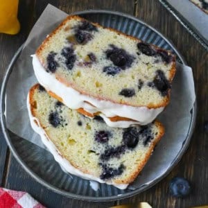 Two pieces of lemon blueberry bread on a plate with a fork.