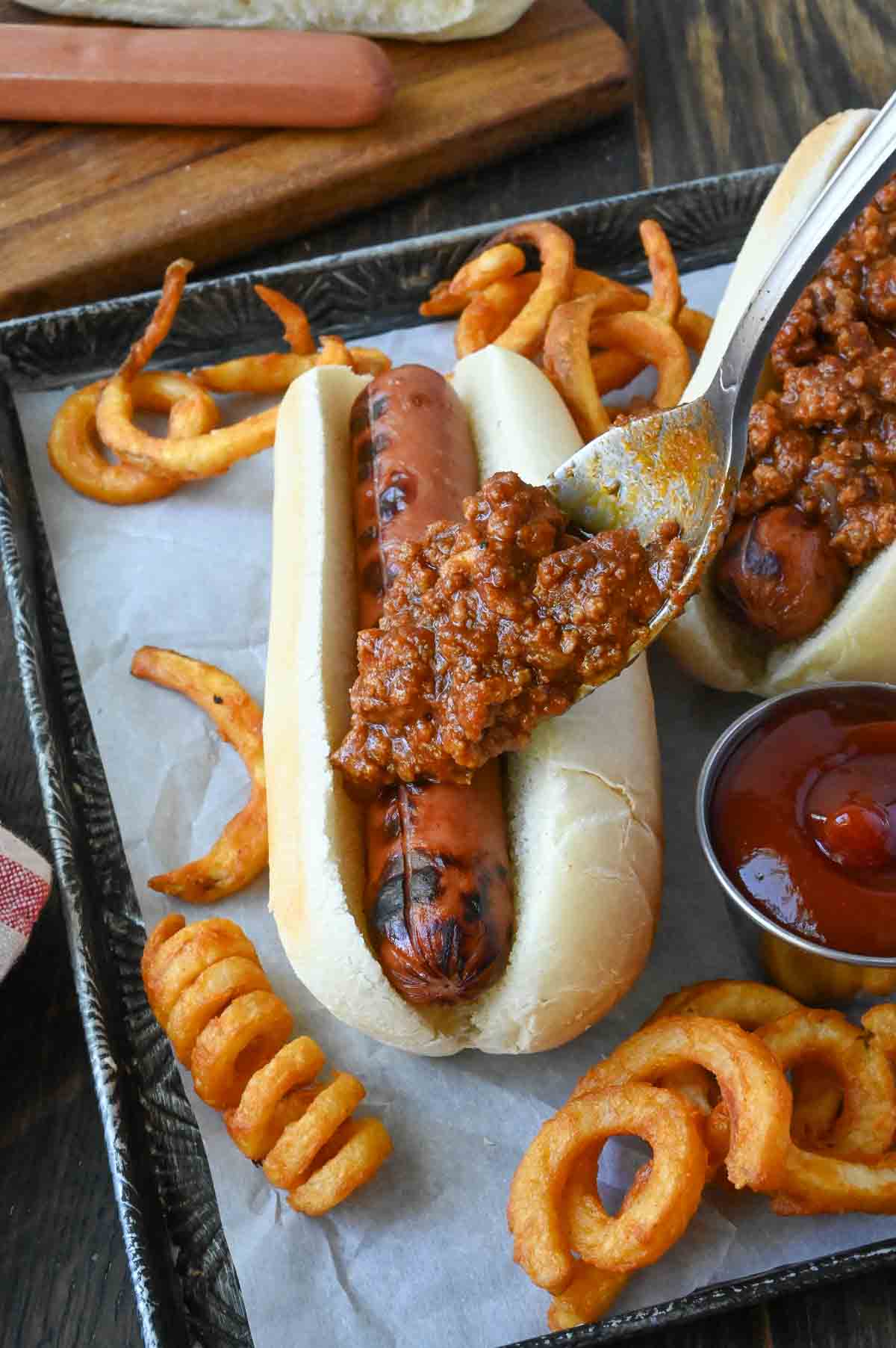 Hot dog chili sauce added on a hot dog.