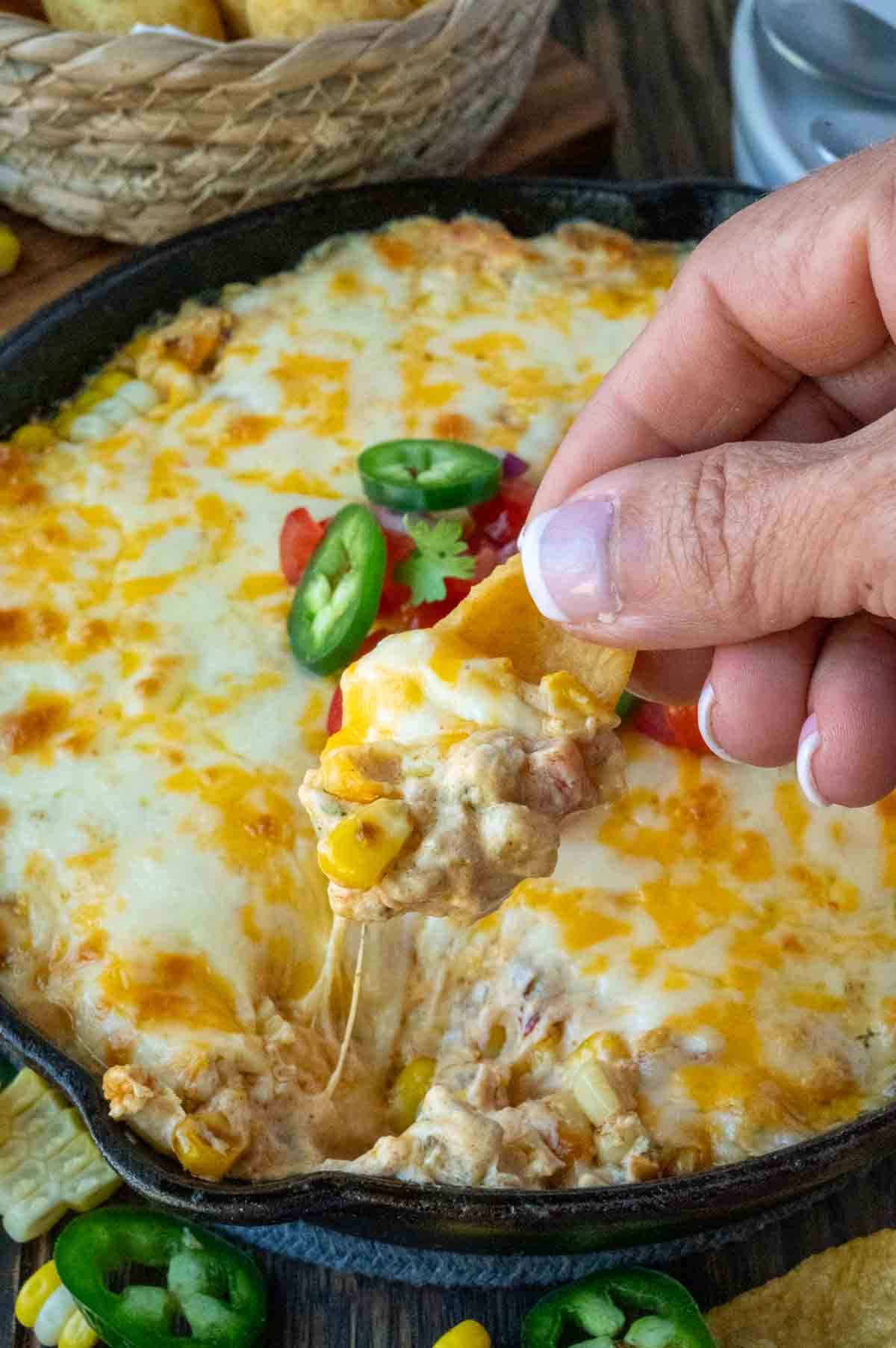 Scooping jalapeno corn dip with a corn chip.