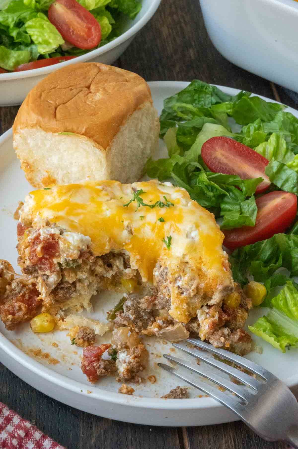 A serving of beef casserole on a plate with a salad.
